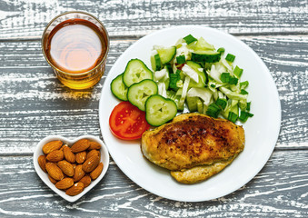 Diet lunch, dinner. Chicken with fresh vegetables, almond nuts and juice. On a wooden background.