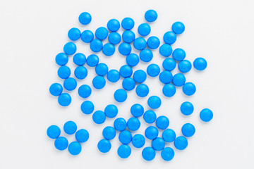 Group of small blue coated chocolate candies similar to m&ms displayed randomly, with soft focus, isolated on white background, top view
