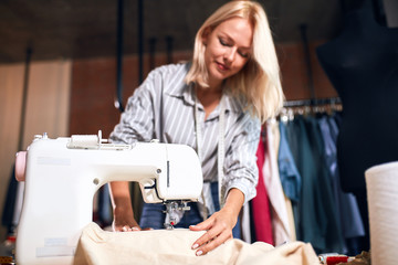 smiling lovely tailor testing new modern sewing machine. close up photo. focus on sewing machine.technology