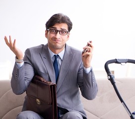 Businessman looking after newborn baby at home and teleworking