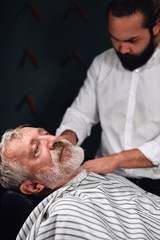 Obraz premium stylist covering senior man's body with a towel before making a new hairstyle. close up photo