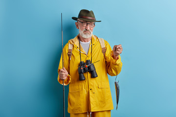 depressed old man is crying . he couldn't catch many fish, close up photo. isolated blue background, studio shot