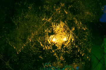 Multi-colored abstraction: water flowing down the glass with reflection of night lights.