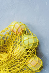 Fresh ripe apples in a trendy yellow cotton string bag.
