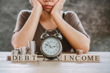 stress Asian woman worry about imbalance income and debt with some coin,clock and calculator on...