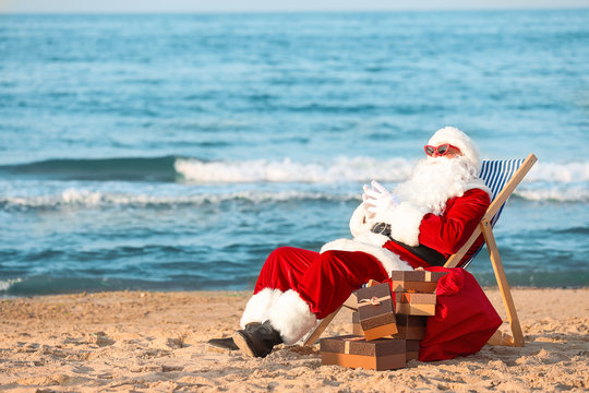 Happy Santa Claus with gifts at sea resort - Powered by Adobe