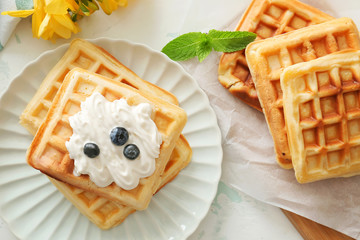 Tasty waffles with cream on table