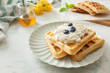 Plate with tasty waffles on white table