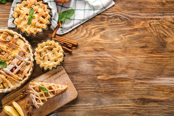 Tasty apple pies on wooden table