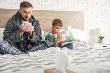 Obraz premium Father and his little son ill with flu at home