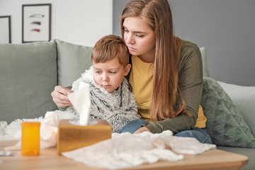 Obraz na płótnie Canvas Woman measuring temperature of her sick son at home