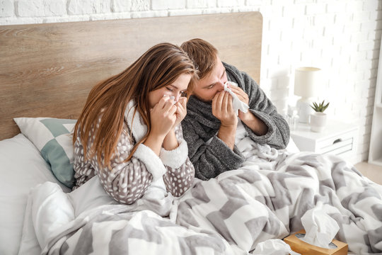 Sick young couple in bed at home