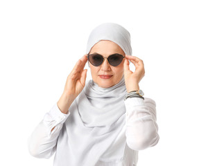 Beautiful mature Muslim woman wearing sunglasses on white background