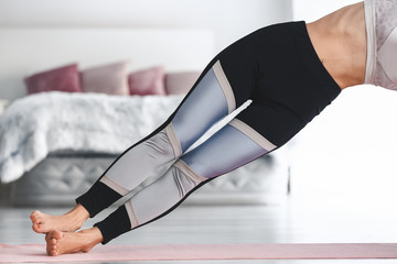 Young woman practicing yoga in bedroom