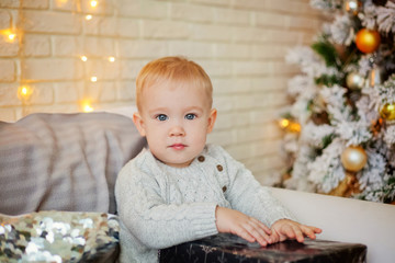 child with a Christmas gift sitting on the couch near the Christmas tree