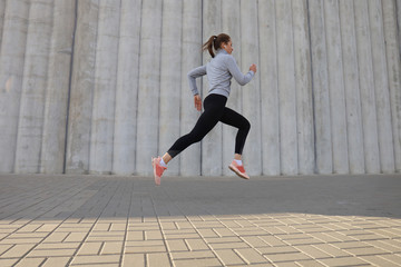 Fototapeta na wymiar Young attractive woman with perfect slim body running outdoors. Fitness and running concept