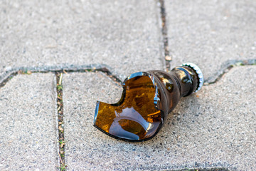 Zerbrochene braune Bierflasche liegt in Scherben am Boden und zeigt die Bekämpfung der...