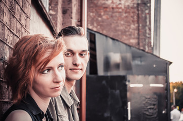 couple in love against a brick wall, a playful and flirting look and a romantic relationship