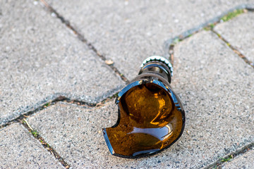 Zerbrochene braune Bierflasche liegt in Scherben am Boden und zeigt die Bekämpfung der...