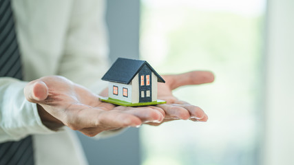 Hand of man holding a toy house. Home safety , Home care , Home for sale concept.