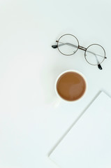 Top view desktop with coffee cup, glasses and blank magazine with copy space. Vertical shot