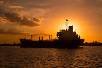 Logistics and transportation of International Container Cargo ship in the ocean at sunset,and silhouette of boat