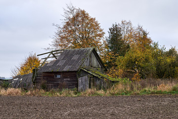 Old wooden abandoned farmstead in the middle of the field in Lithuania.