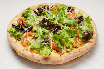 Italian pizza with spinach and lettuce, on a white wooden table