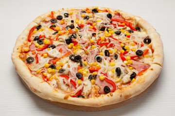 Italian pizza with slices of sausage, tomatoes, sweet pepper and corn, on a wooden board