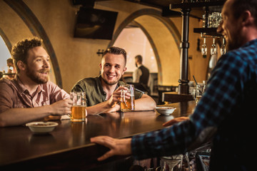 Cheerful friends drinking draft beer in a pub