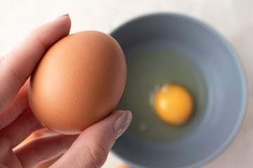 Woman holds brown organic egg, top view. Going to make an omelet from chicken eggs, farm product. Breakfast cooking concept