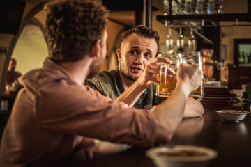 Cheerful friends drinking draft beer in a pub