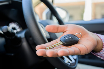 Fototapeta premium Close up male hand showing car key while sitting in car.