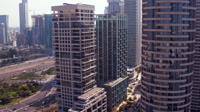 Aerial drone shot (rotating and panning motion) in broad daylight: skyscrapers from the cityscape of the residential neighborhood of Park Tzameret in Tel Aviv, Israel.