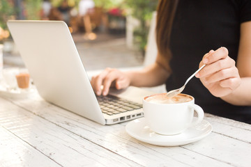 A woman is working with a computer and a coffee drink on a white table,blurred background of a business girl