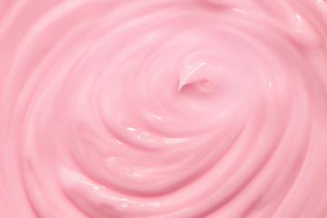 Texture of a moisturizing or cosmetic cream pink for the face or body. Top view. Cream swirl...