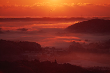 雲海に沈む町。山間部の町（日本）に発生した雲海が、朝日で真っ赤に染まる風景写真