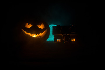 Fototapeta premium Horror view of Halloween pumpkin with scary smiling face. Head jack lantern with spooky building