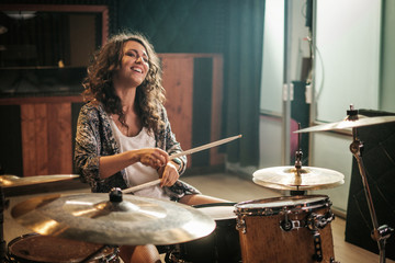 Woman playing drums during music band rehearsal