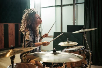 Tuinposter Woman playing drums during music band rehearsal © Nejron Photo