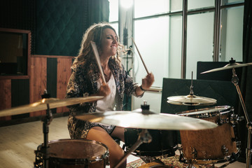 Woman playing drums during music band rehearsal