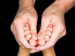 Fototapeta premium Feet of caucasian child in hands of dertmatologist doctor isolated towards black