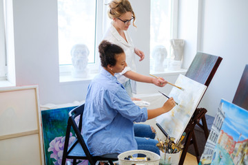 Creative painter and her protege working in a studio