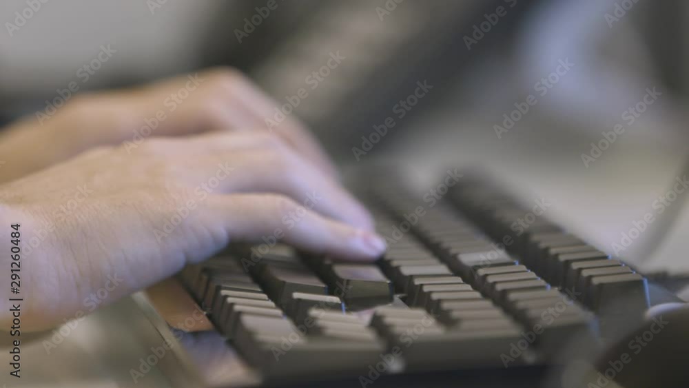 Poster man hands typing on computer keyboard. handheld. rack focus. slowmo