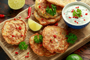 Corn fritters, pancake with dip white sauce, lime and chilli on wooden board