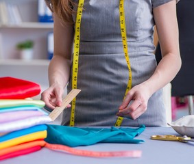 Woman tailor working on a clothing sewing stitching measuring fa