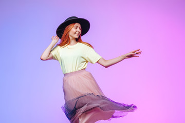 Red-haired girl in the wind holds a hat