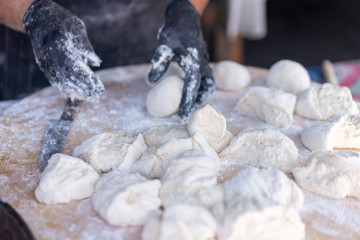 Chef in black gloves cuts raw dough into pieces make pizza Patties bread.