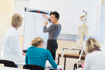 Obraz premium student identifying bones on a flipchart skeleton beside her
