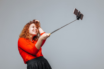 Redhead girl taking selfie on phone on monopod